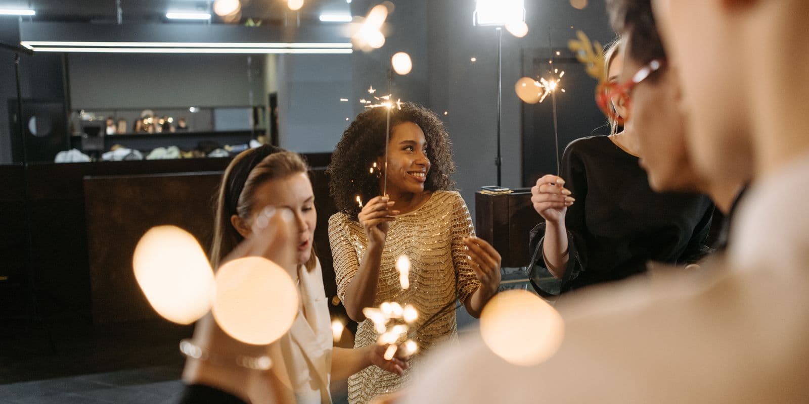 Friends laughing together while holding sparklers at a party