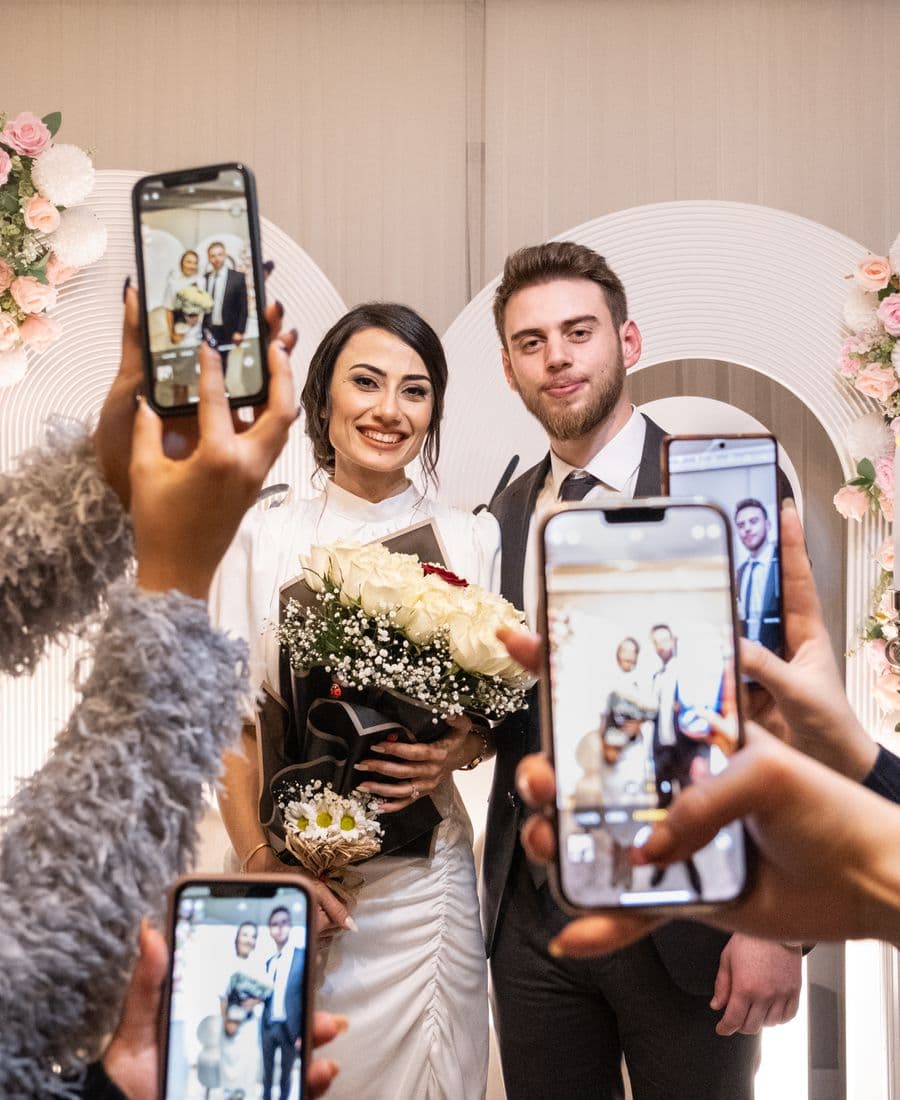 Guests photographing the newlyweds on their phones at a wedding celebration